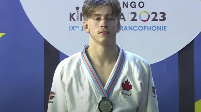 Un judoka avec sa médaille d'or est sérieux sur un podium.