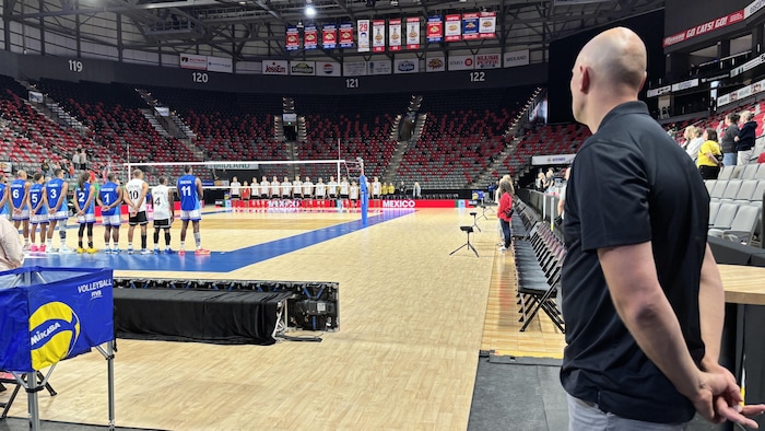 Davin, de dos, regarde les joueurs de deux équipes qui s'apprêtent à jouer un match.