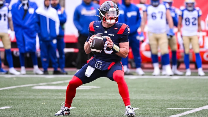 Un quart-arrière tient le ballon dans sa main droite pendant qu'il cherche une cible.