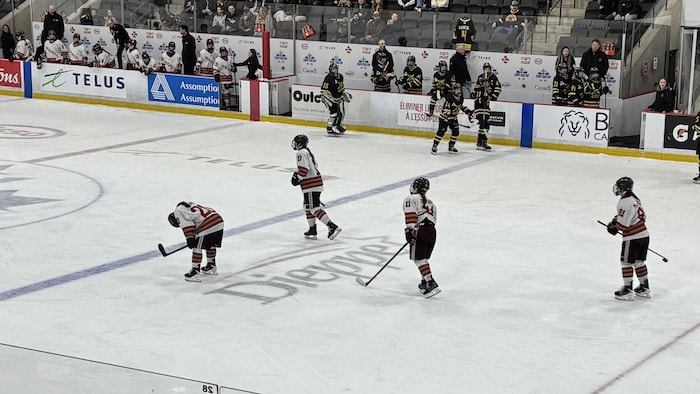 Des joueuses sur la glace, dont une est appuyée sur ses genoux.