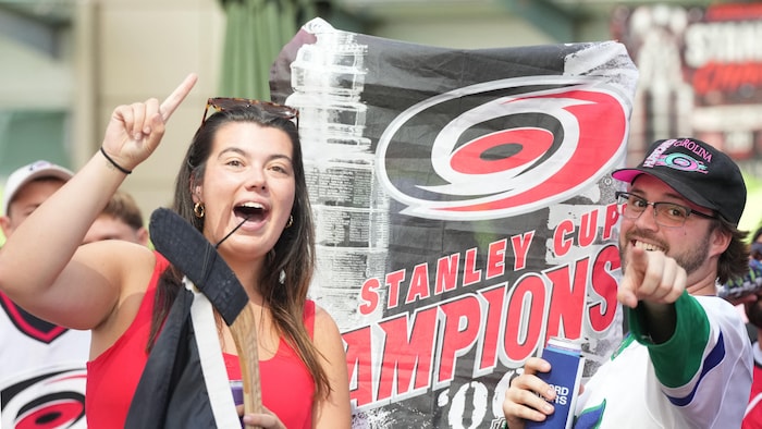 Une femme et un homme tiennent une banderole aux couleurs des Hurricanes de la Caroline.