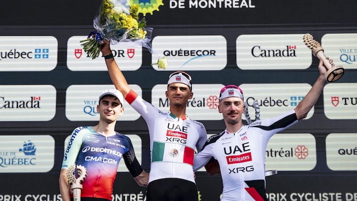 Trois cyclistes posent pour une photo sur le podium.