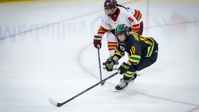 Deux joueuses regardent une rondelle devant elles.