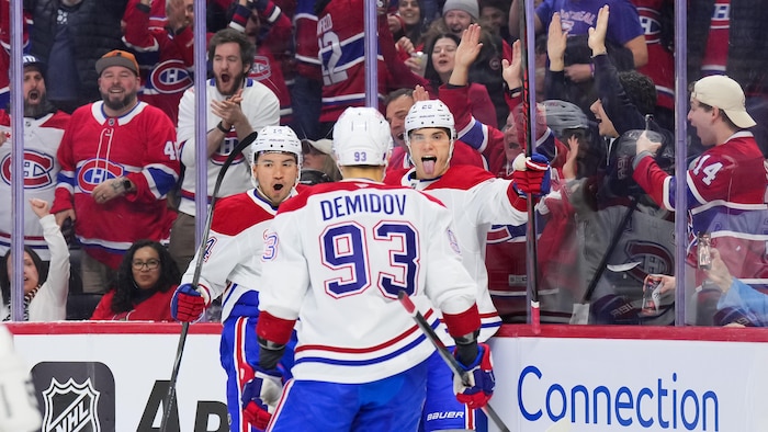Trois joueurs de hockey se font l'accolade.