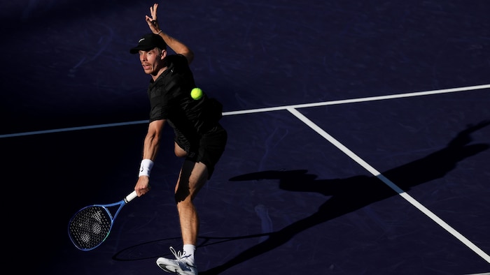 Un joueur de tennis frappe un revers.