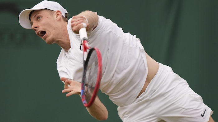 Un joueur de tennis effectue un service.