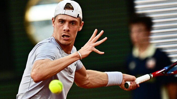 Un joueur de tennis fixe intensément des yeux la balle qu'il s'apprête à frapper.