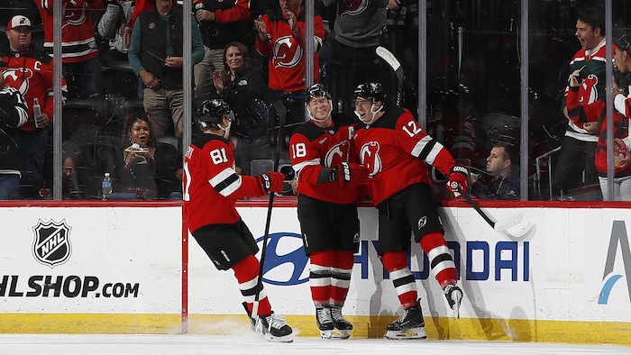 Trois joueurs de hockey célèbrent un but.