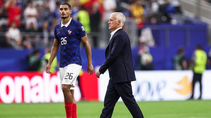 Un joueur de soccer et son entraîneur marchent sur le terrain.