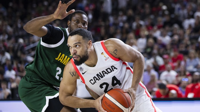 Un basketteur avec le ballon évite un adversaire.