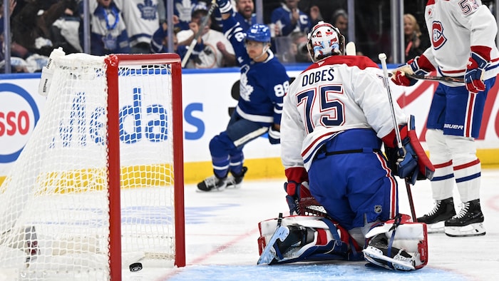 Un gardien de hockey regarde le joueur qui l'a déjoué au loin.