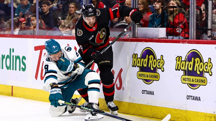 Deux joueurs de hockey se disputent la rondelle. 