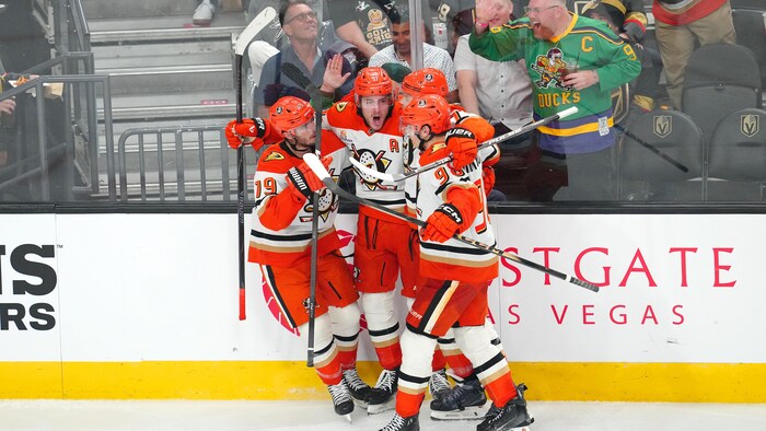 Un groupe de joueurs d'Anaheim célèbre un but le long de la baie vitrée.