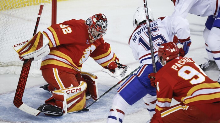 Un gardien de but effectue un arrêt contre un hockeyeur.