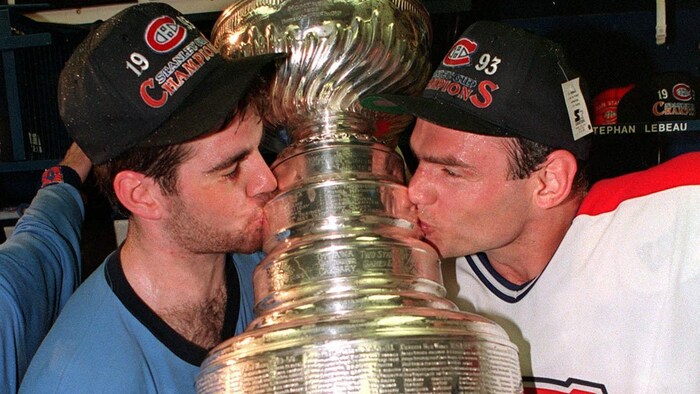 Deux joueurs de hockey embrassent le trophée.
