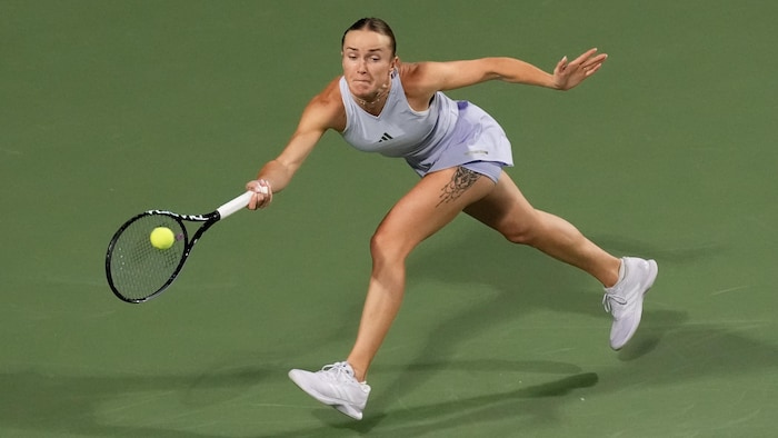 Une joueuse de tennis s'étire pour frapper la balle. 