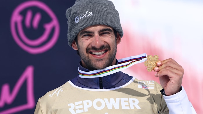 Il tient fièrement une médaille d'or.