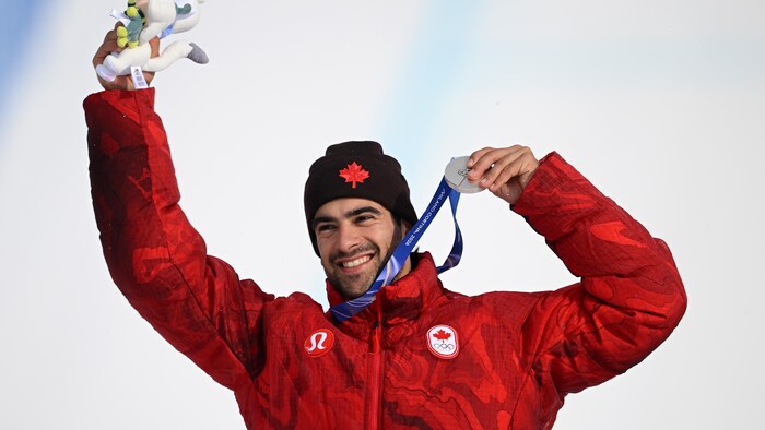 Sur le podium, il tient sa médaille d'argent avec un grand sourire.