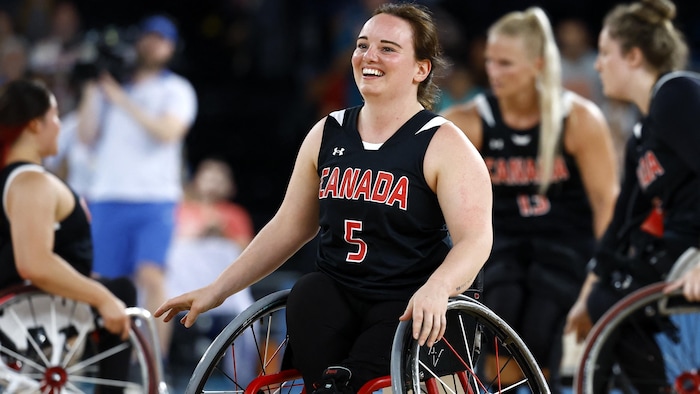 Une athlète en fauteuil roulant sourit après un point.
