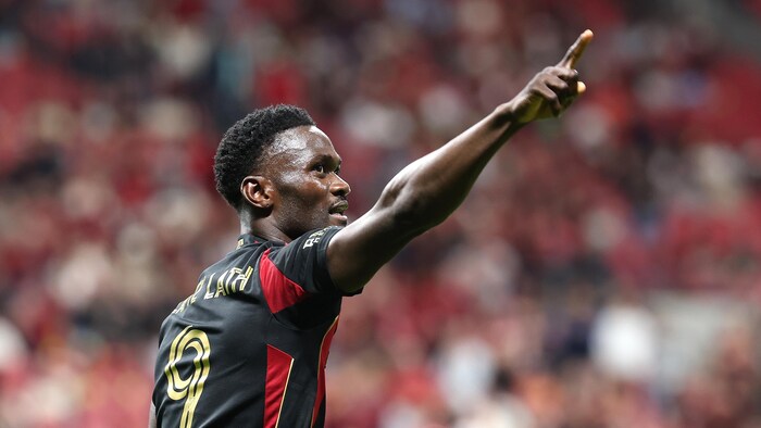 Un joueur de soccer pointe dans les airs. 