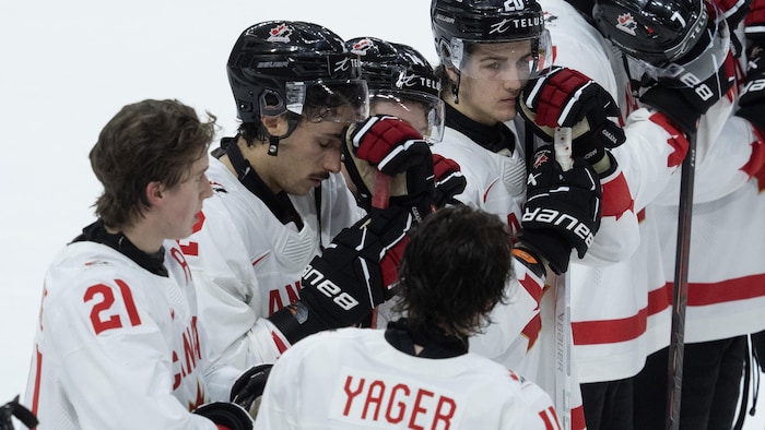 Des jeunes joueurs de hockey sont alignés et sont déçus.