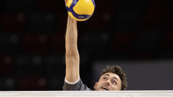 Il saute haut et frappe le ballon par-dessus le filet.