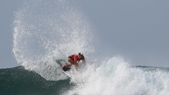 Une surfeuse sur une vague.