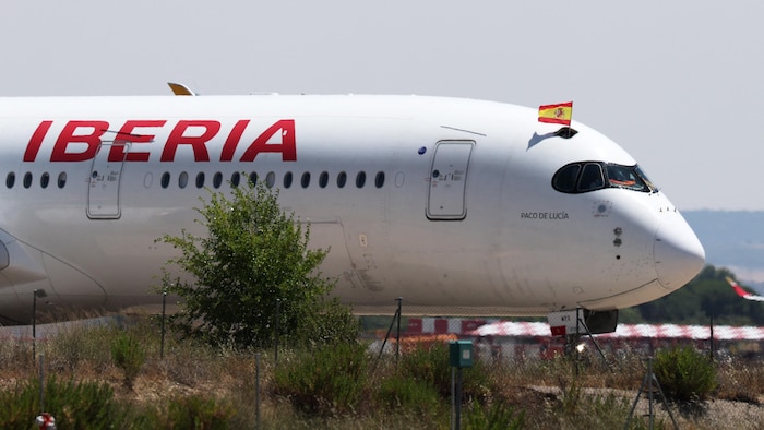 Un drapeau de l'Espagne est brandi à travers une trappe du fuselage de l'appareil.