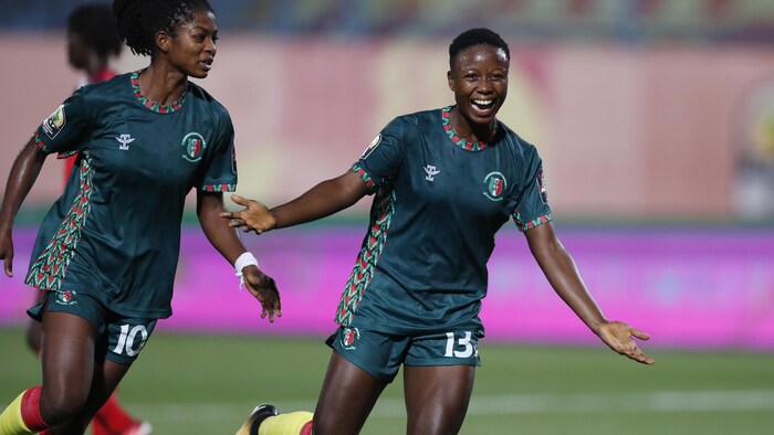 Une joueuse de soccer célèbre un but en levant les bras.