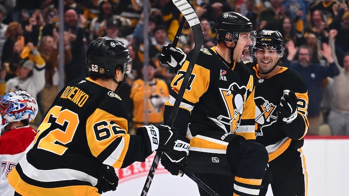 Trois joueurs de hockey célèbrent un but.