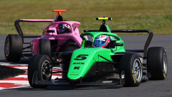 Deux pilotes de formule 4 prennent un virage sur la piste.