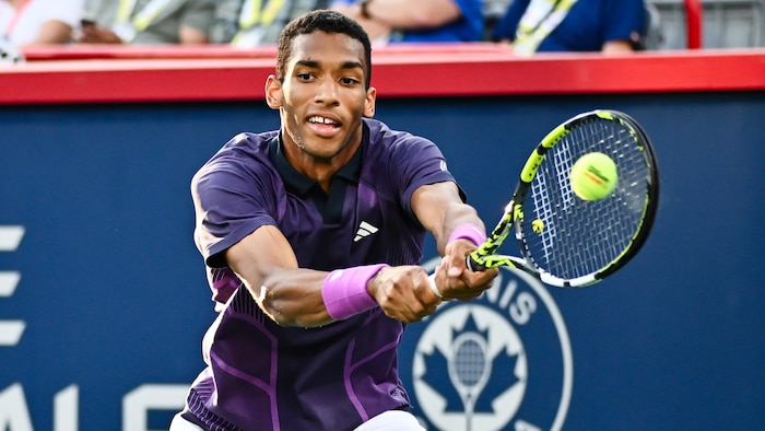Le joueur de tennis Félix Auger-Aliassime s'étire pour frapper la balle avec sa raquette.