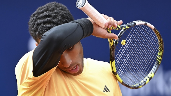 Un joueur de tennis s'essuie le front avec son avant-bras droit.