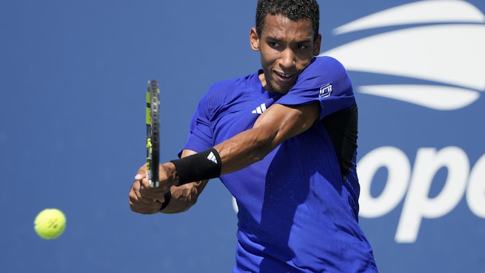 Un joueur de tennis retourne une balle du revers.