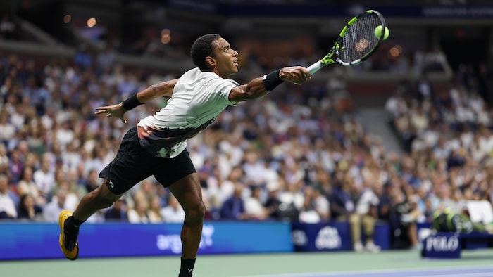 Un joueur de tennis s'étire pour atteindre la balle avec sa raquette.
