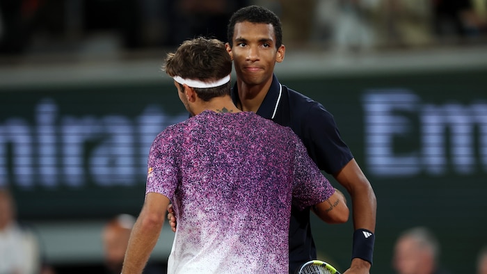 Deux hommes se donnent la main au filet après un match de tennis. 
