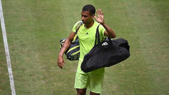 Un joueur de tennis quitte le terrain, ses bagages à la main.