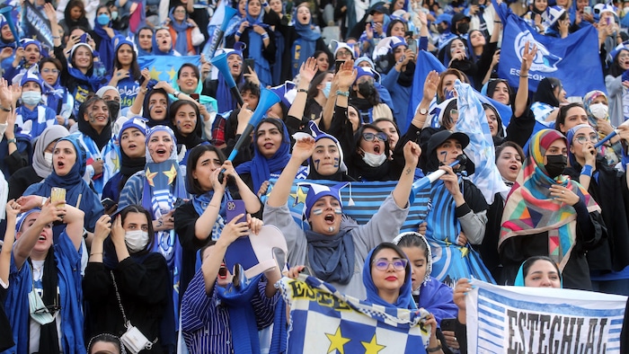Des femmes, vêtues aux couleurs de l'équipe, crient et gesticulent. 