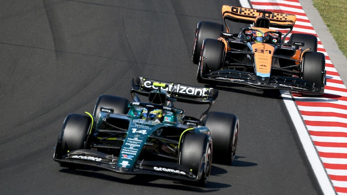 Deux monoplaces de F1 se suivent sur un circuit et s'apprêtent à tourner à droite.