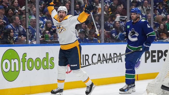 Un joueur de hockey lève les bras pour célébrer un but.
