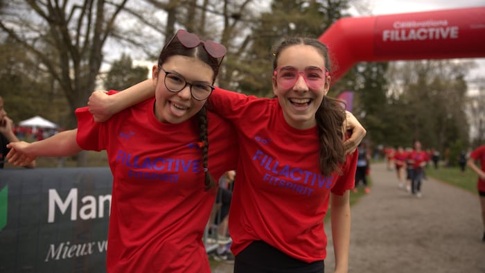 Deux adolescentes se tiennent par le cou et sourient.