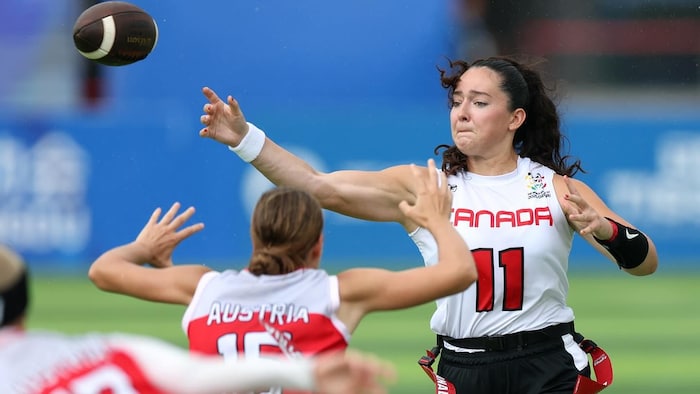 Une joueuse de flag football décoche une passe pendant qu'une adversaire s'approche d'elle.