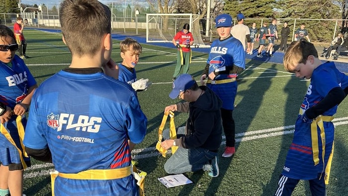 Un entraîneur distribue des ceintures de flag football à de jeunes joueurs.