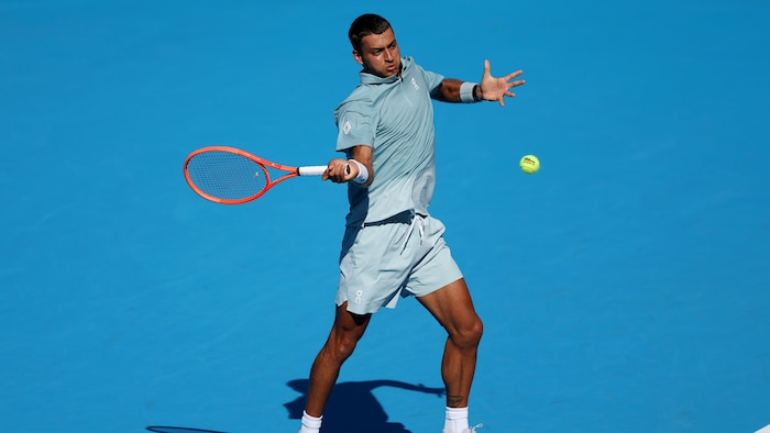 Un joueur de tennis frappe un coup droit. 