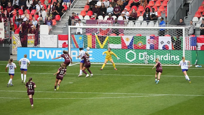Une joueuse de soccer marque un but de la tête pendant un match professionnel.