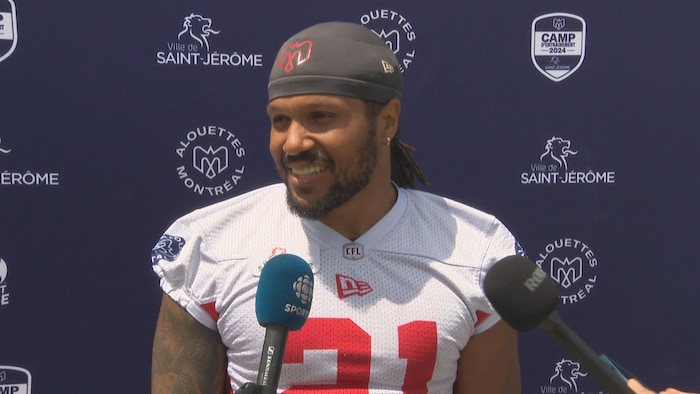 Il répond aux questions des journalistes.