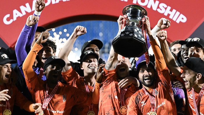 Les joueurs célèbrent trophée en main.