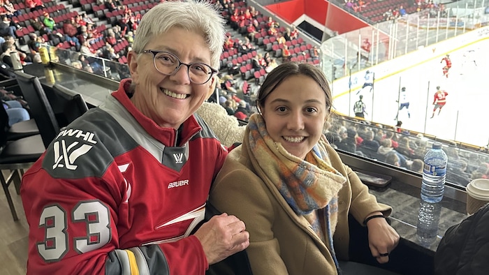 Une partisane de hockey prend une photo avec une joueuse professionnelle.