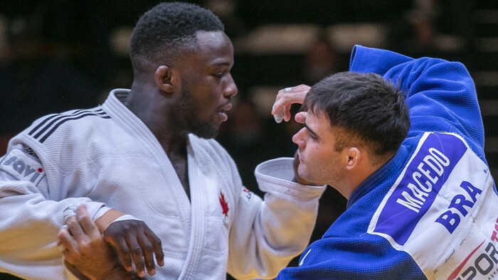 Un judoka, de profil, tient son adversaire par le col de son judogi. 