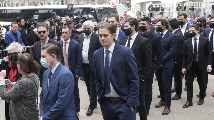 Des hommes habillés en veston et cravate marchent.